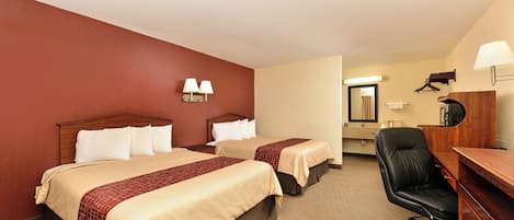 A hotel room with two beds, a desk, a chair, and a bathroom visible through an open door.