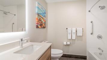 A modern bathroom with a sink, toilet, shower, and a painting on the wall.