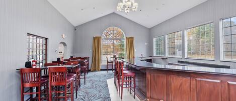 A modern dining area with a bar, wooden chairs, and a patterned floor.