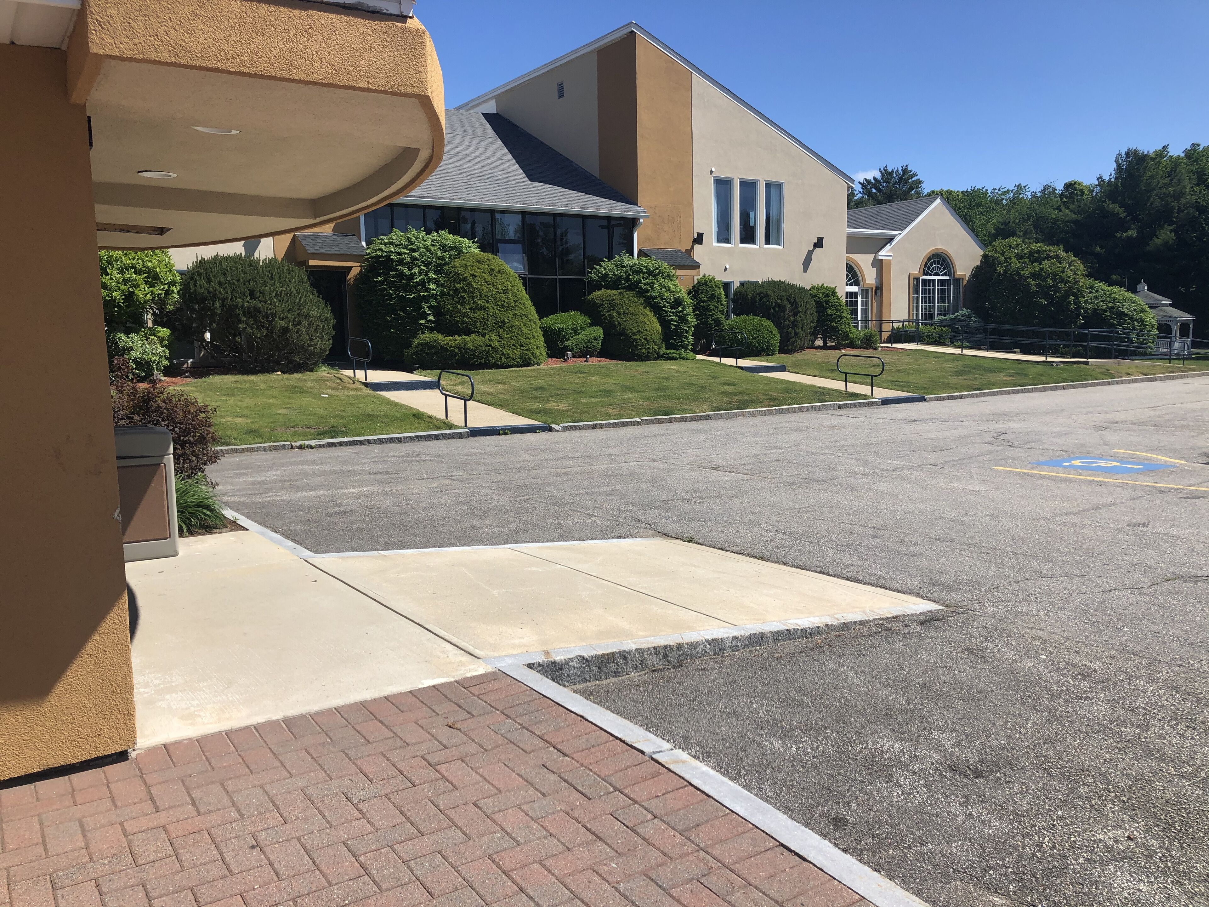 A parking lot with a handicapped parking space, a building with a modern design, and well-maintained landscaping.