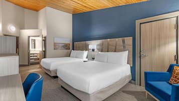 A hotel room with two beds, a desk, a chair, a wardrobe, and a door.