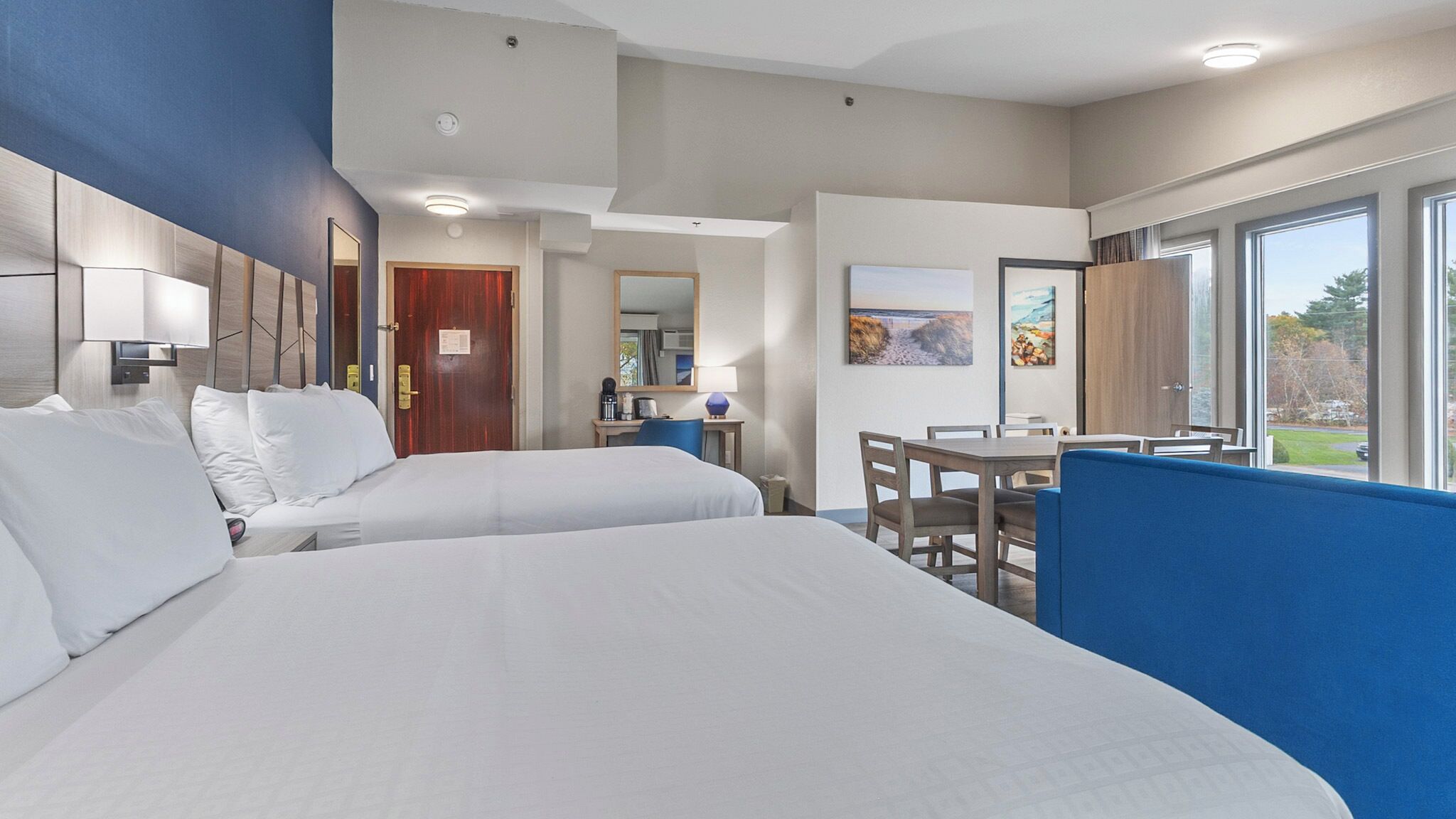 Habitación de hotel con dos camas, un escritorio, una silla y una mesa de comedor.