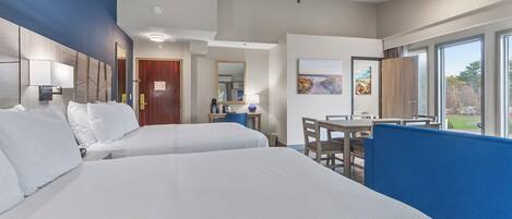 Habitación de hotel con dos camas, un escritorio, una silla y una mesa de comedor.