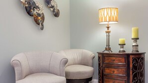 Una habitación con dos sillones, una mesita de madera con una lámpara y dos velas.