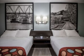 Habitación de hotel con dos camas, una mesita de noche y dos lámparas fijadas a la pared.