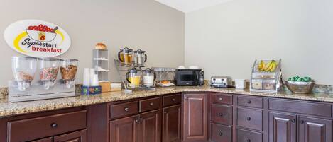 A kitchen with a breakfast station, including a coffee maker, toaster, and various food items.