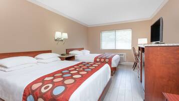 A hotel room with two beds, a desk, a TV, and a window with blinds.