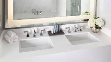 Un baño moderno con dos lavamanos, un espejo grande y un estante de madera con toallas.
