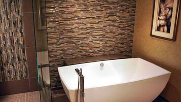 A modern bathroom with a freestanding bathtub, a glass shower enclosure, and a mosaic tile wall.