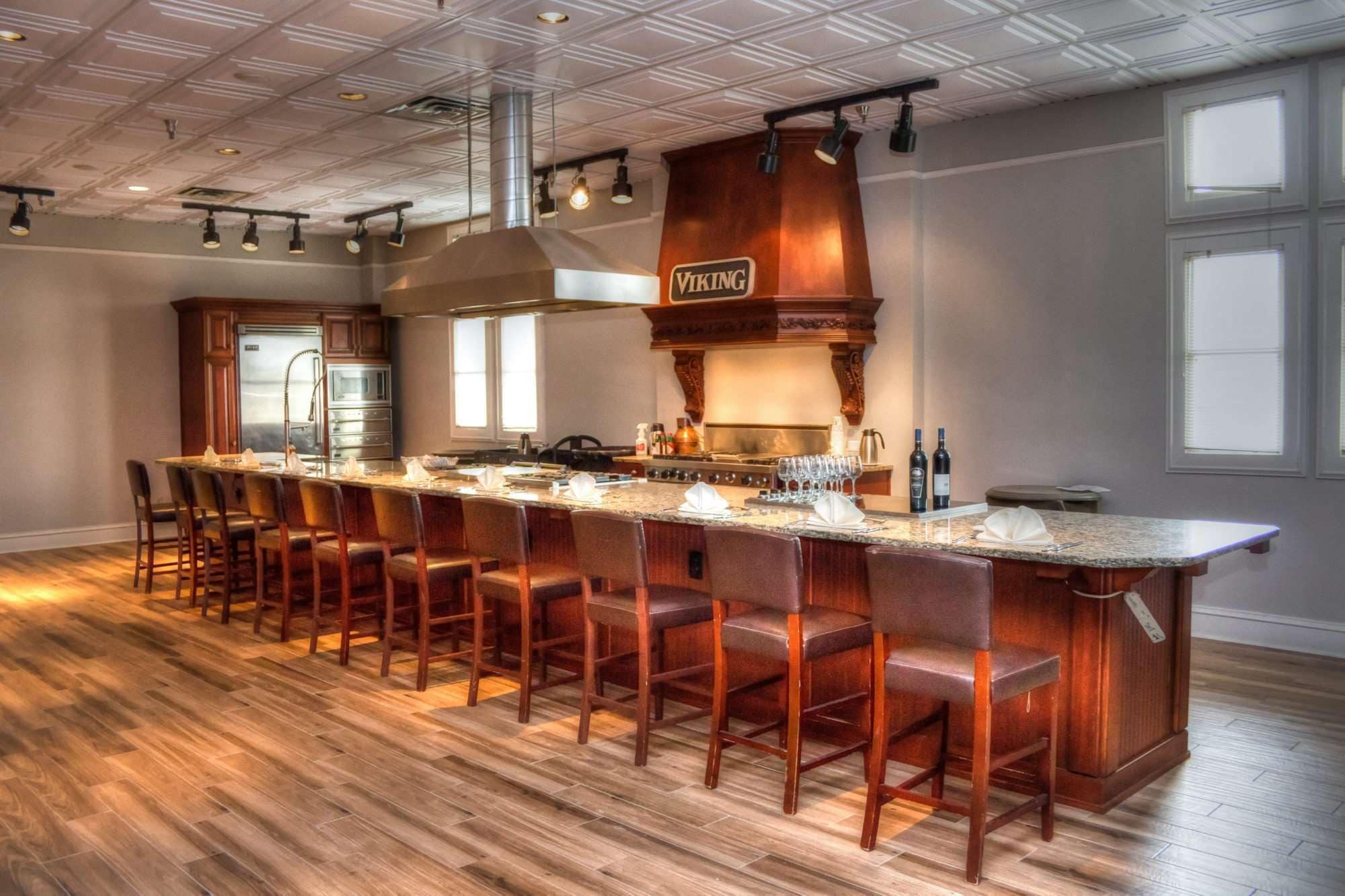 A spacious kitchen with a long island, bar stools, and a Viking logo on the wall.
