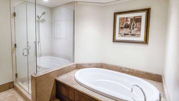 Un baño moderno con ducha envuelta en vidrio, una bañera independiente y un cuadro en la pared.