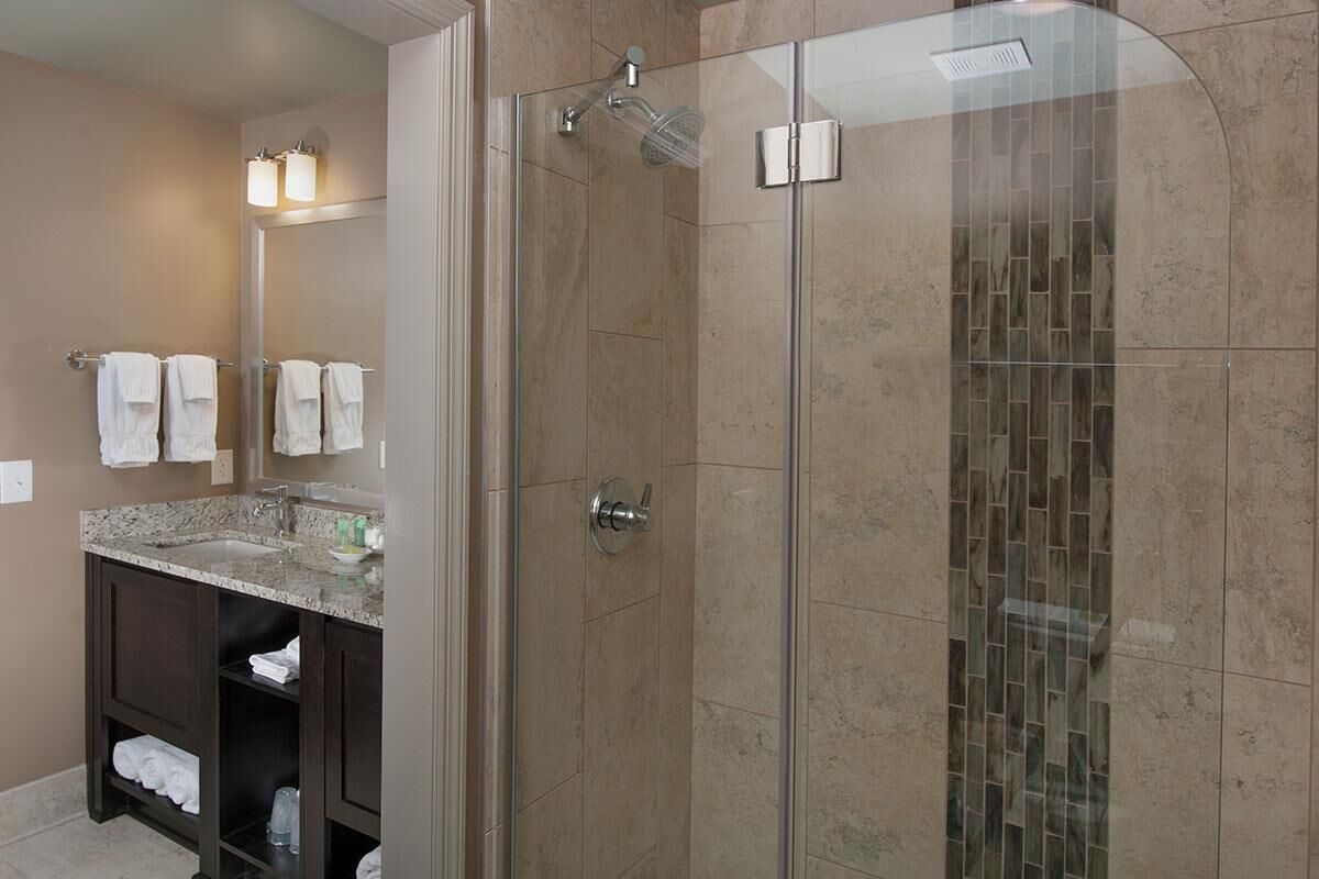 A modern bathroom with a glass-enclosed shower, a vanity with a sink, and a mirror.