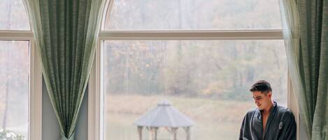Wellnessbereich mit Whirlpool, Kerzen und Blick auf einen Garten durch große Fenster.