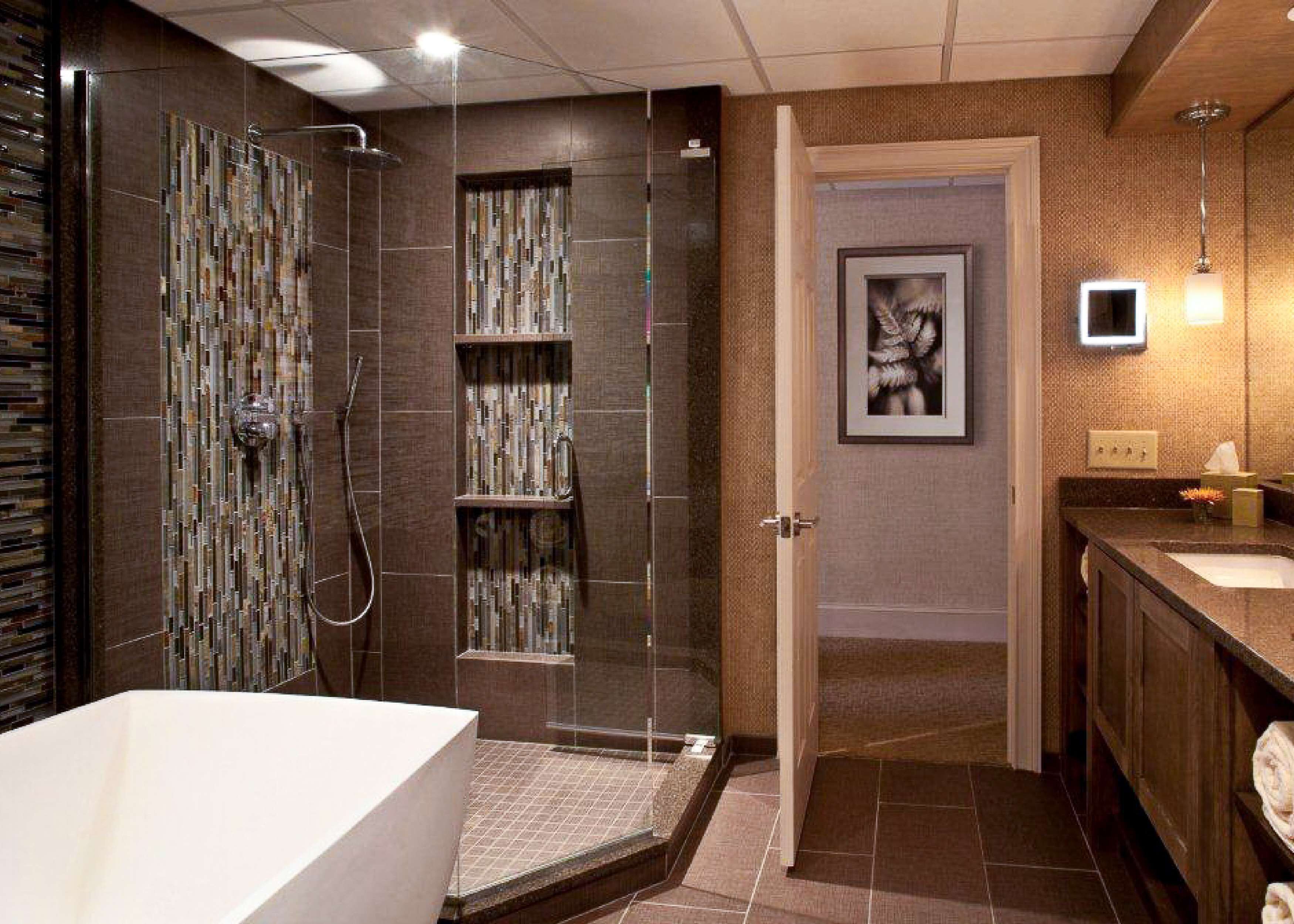 A modern bathroom with a walk-in shower, a glass-enclosed vanity, and a framed picture on the wall.
