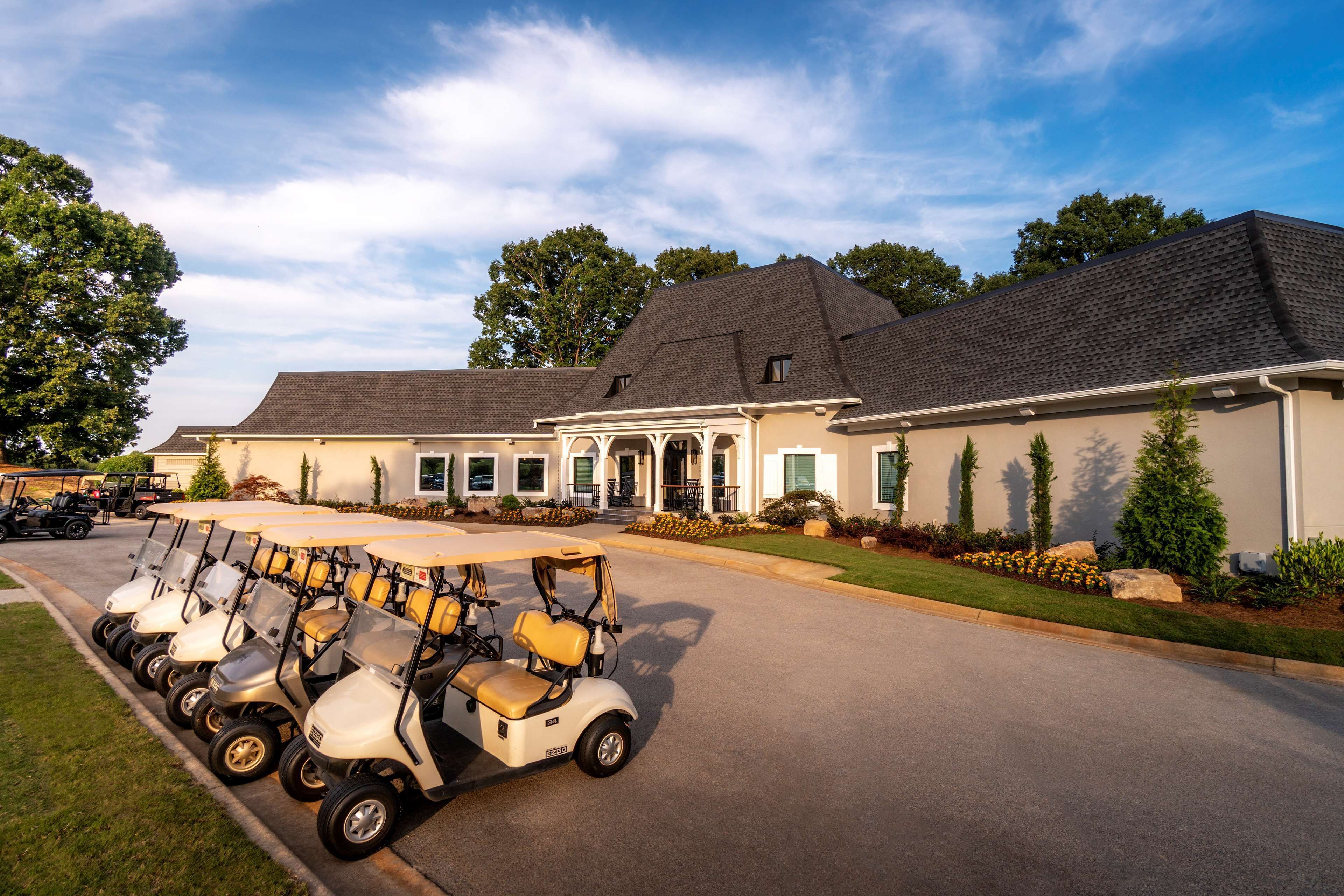 A golf course with multiple golf carts lined up in front of a clubhouse.