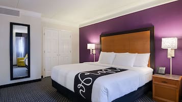 Une chambre d’hôtel avec un grand lit, une tête de lit en bois, deux lampes de chevet, une table de chevet et un miroir au mur.