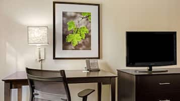 Habitació d'hotel amb escriptori, cadira, televisió de pantalla plana, quadre, làmpada i telèfon.