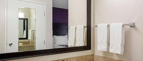 A bathroom with a granite countertop, a white sink, a mirror, and two towels hanging on a towel rack.