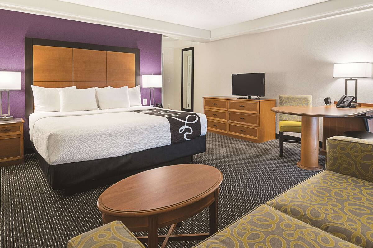Une chambre d’hôtel équipée d’un lit, d’un bureau, d’une chaise, d’une télévision et d’un téléphone.