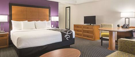 A hotel room with a bed, a desk, a chair, a television, and a telephone.