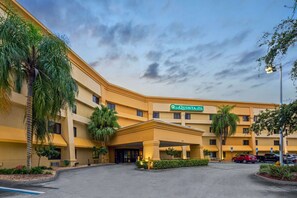 La Quinta Inn & Suites features a modern entrance with a covered area and lush surroundings.
