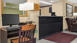 A hotel reception area with a desk, computer, chair, and a reception counter.