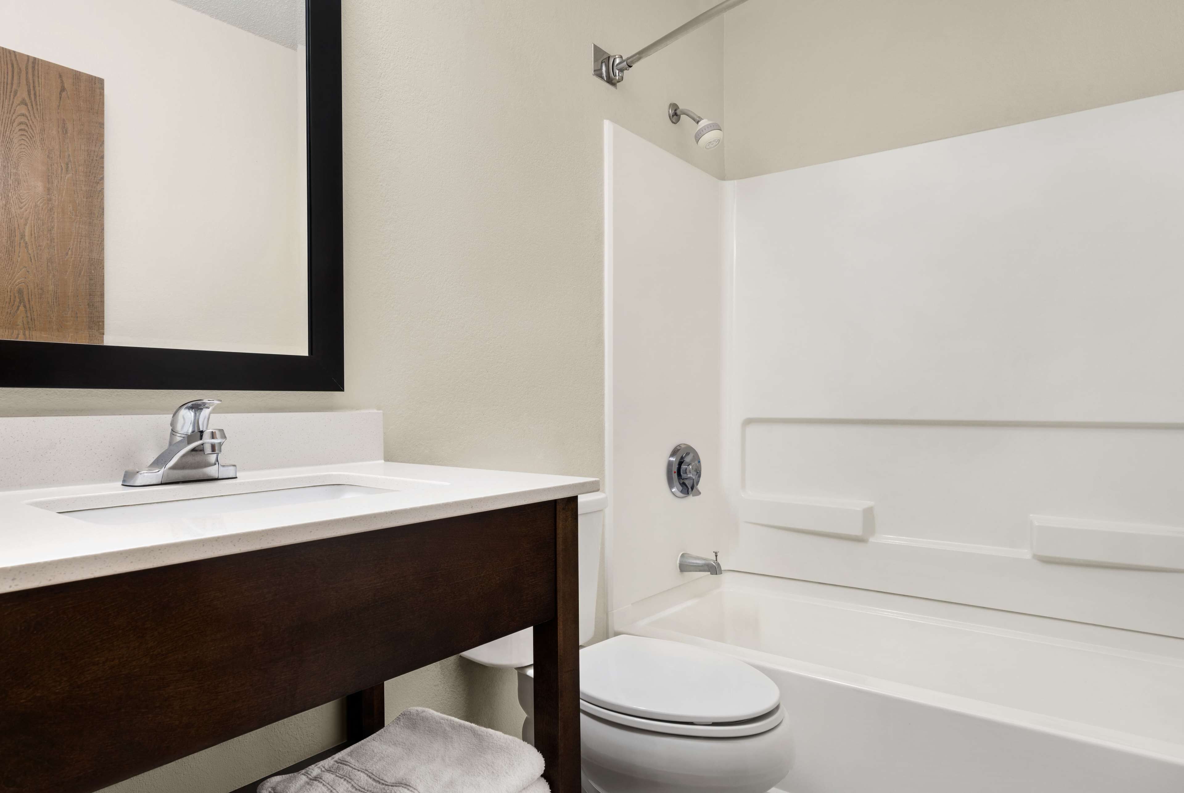 Une salle de bain avec un lavabo blanc, un meuble-lavabo en bois foncé, des toilettes blanches et une baignoire blanche.
