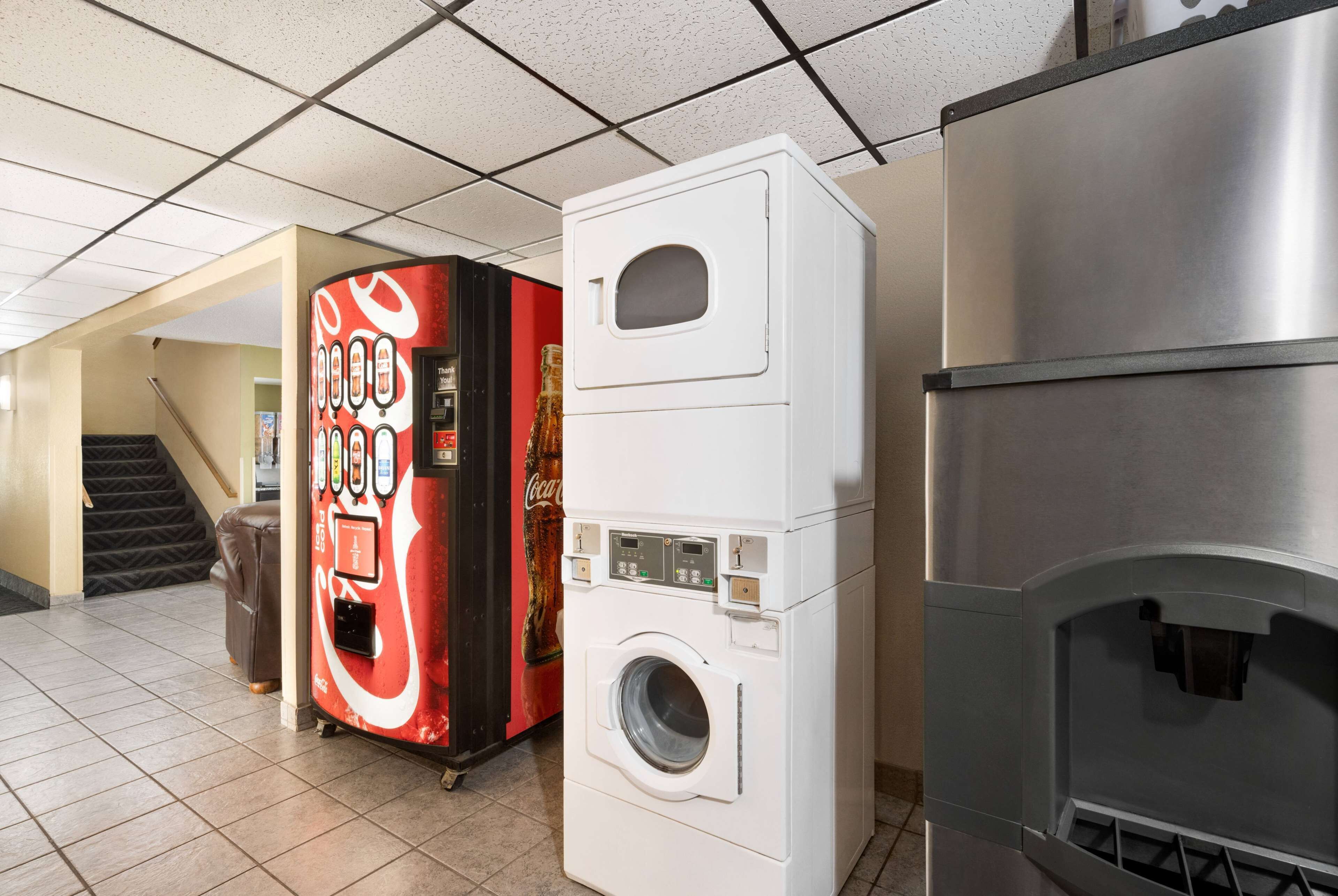 A commercial space with a vending machine, a stacked washer-dryer unit, and a stainless steel appliance, likely a grill or oven.