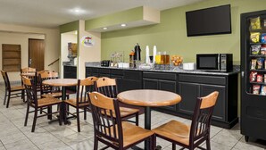 A restaurant with a counter, chairs, a TV, and a vending machine.