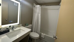 Un baño con lavamanos blanco, espejo, inodoro y cortina de ducha.