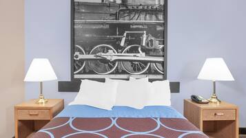 A hotel room with a bed, two nightstands with lamps, a framed picture on the wall, and a telephone on one of the nightstands.