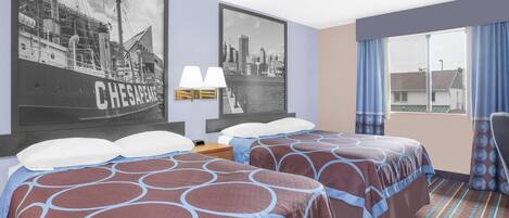 A hotel room with two beds, a cityscape poster, a window with curtains, and a view of buildings outside.