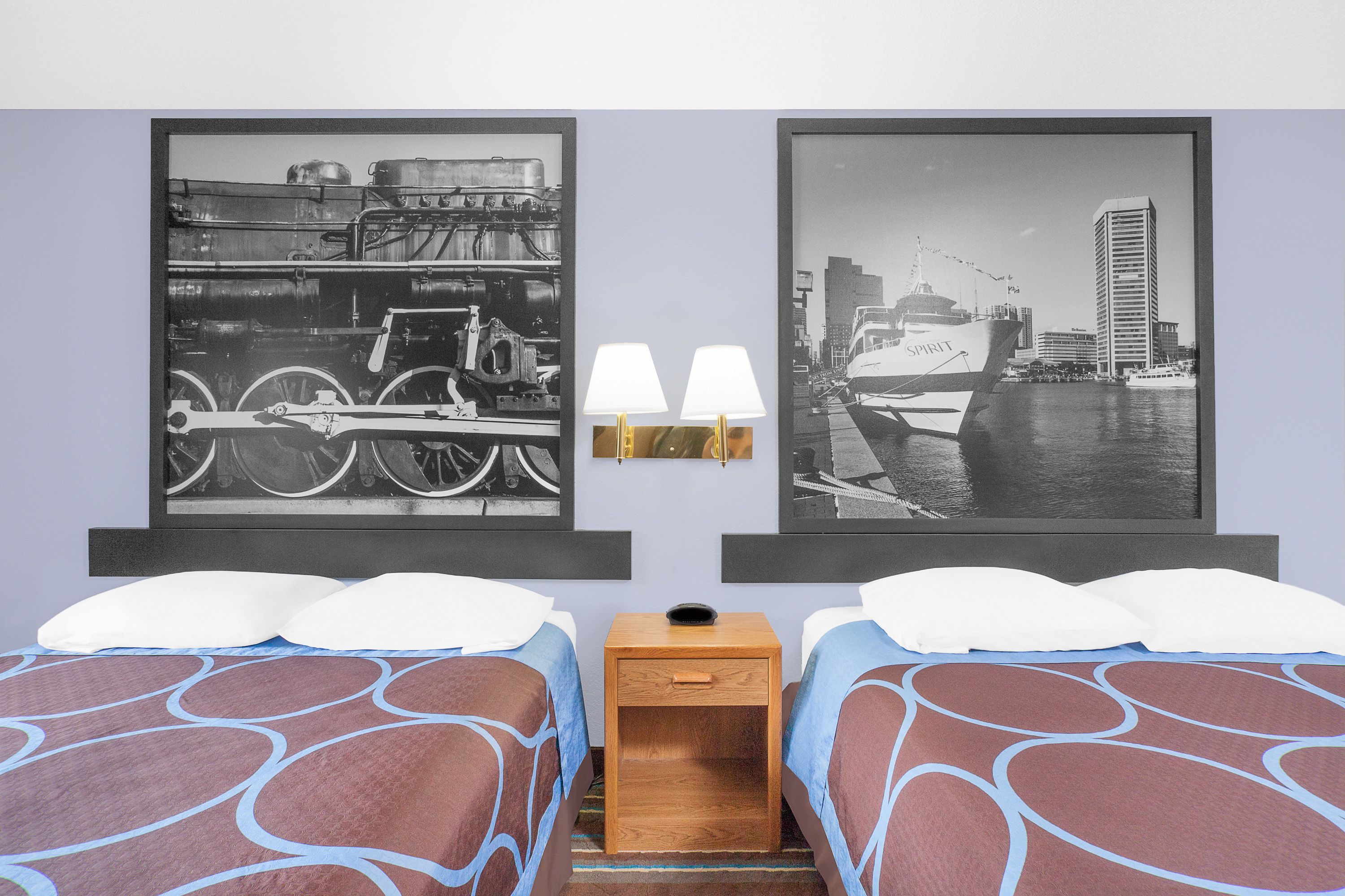 Una habitación de hotel con dos camas, una mesita de noche y dos lámparas de pared.