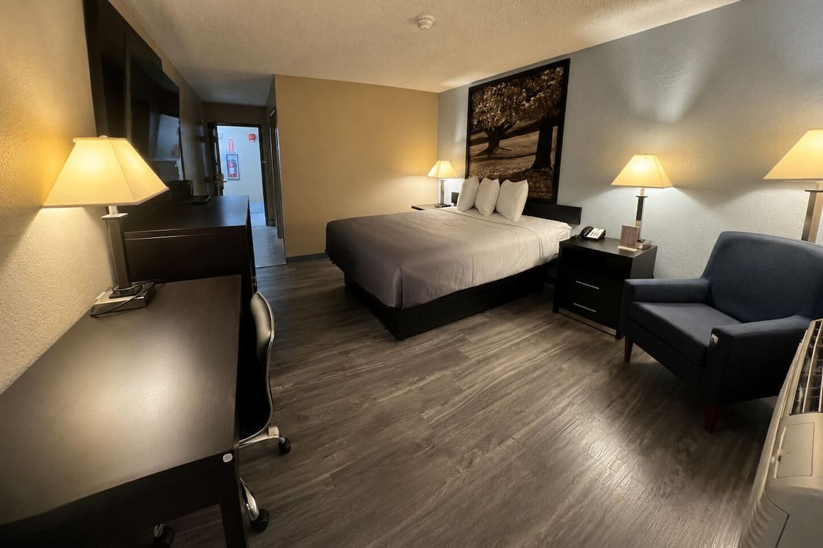 Habitació d'hotel amb un llit, escriptori, cadira i dues làmpades de nit.