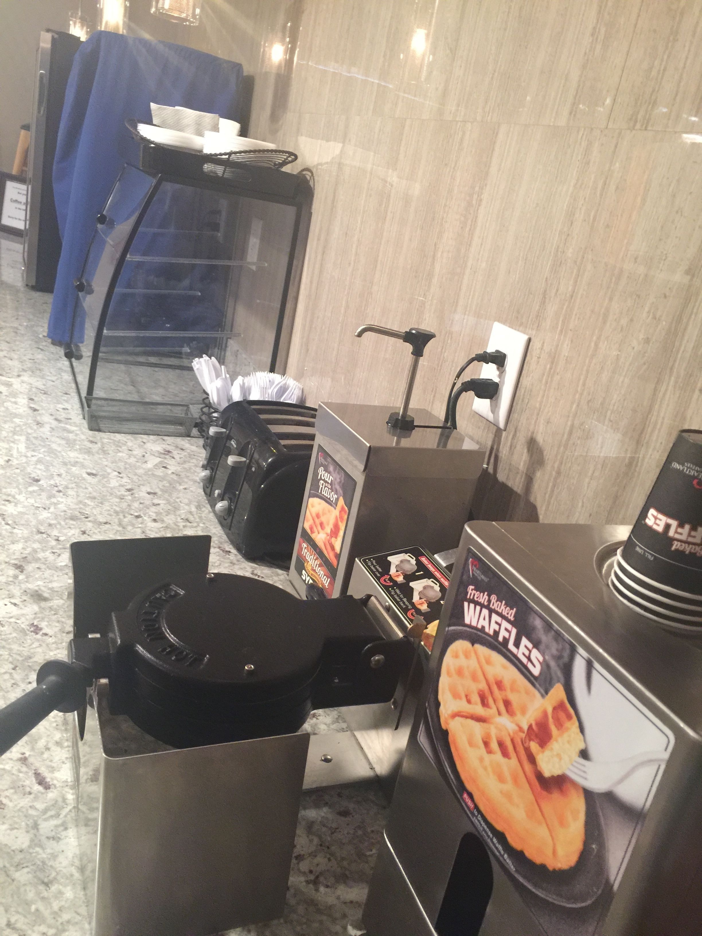 A waffle maker with a sign for fresh baked waffles.