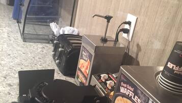 A waffle maker with a sign for fresh baked waffles.