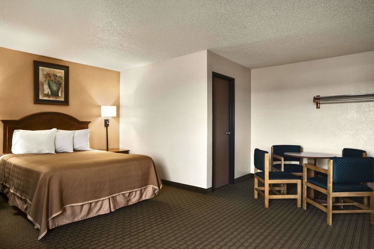A hotel room with a bed, a desk, and two chairs.