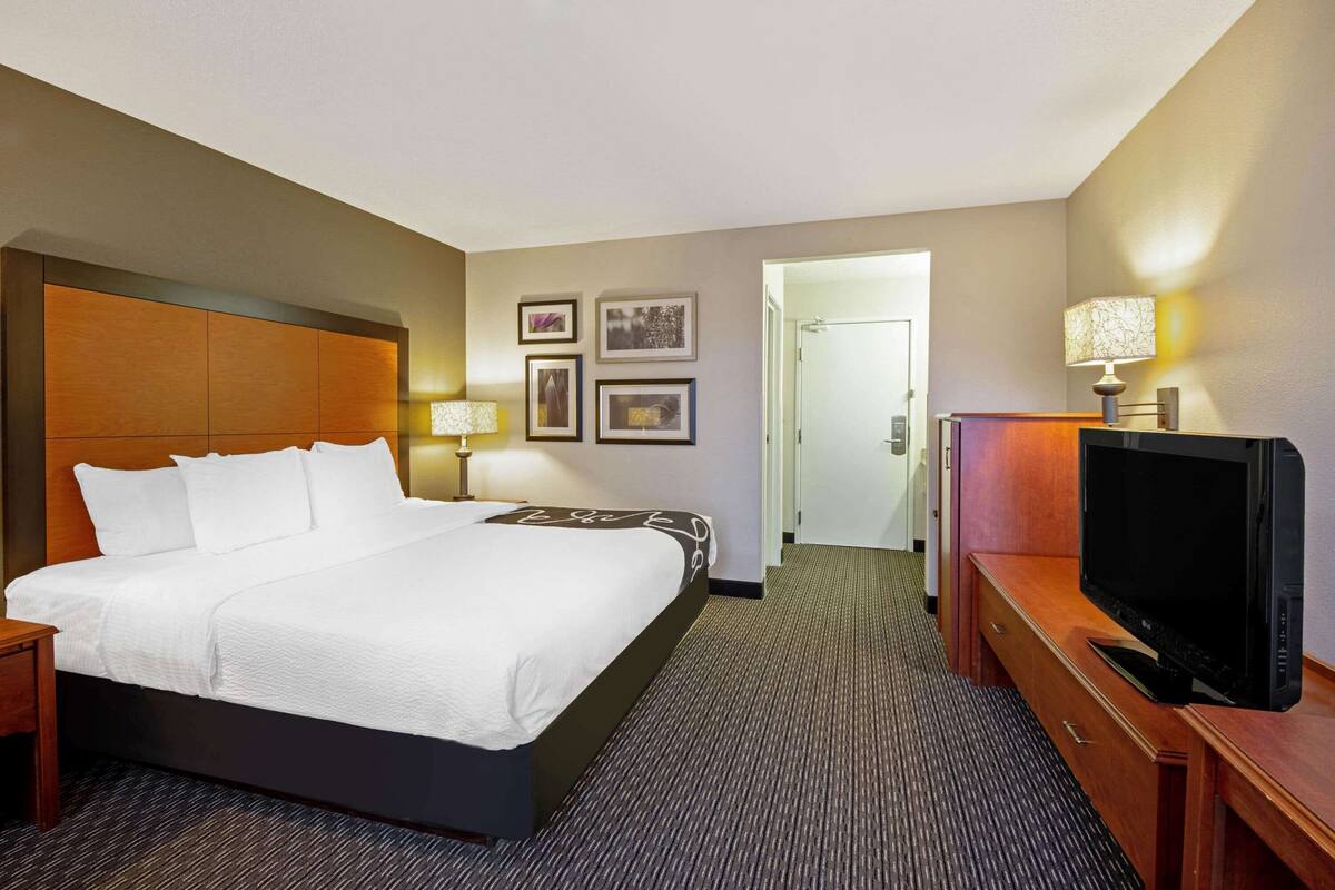 Ein Hotelzimmer mit einem großen Bett, einem Fernseher, einem Schreibtisch und einer Lampe.