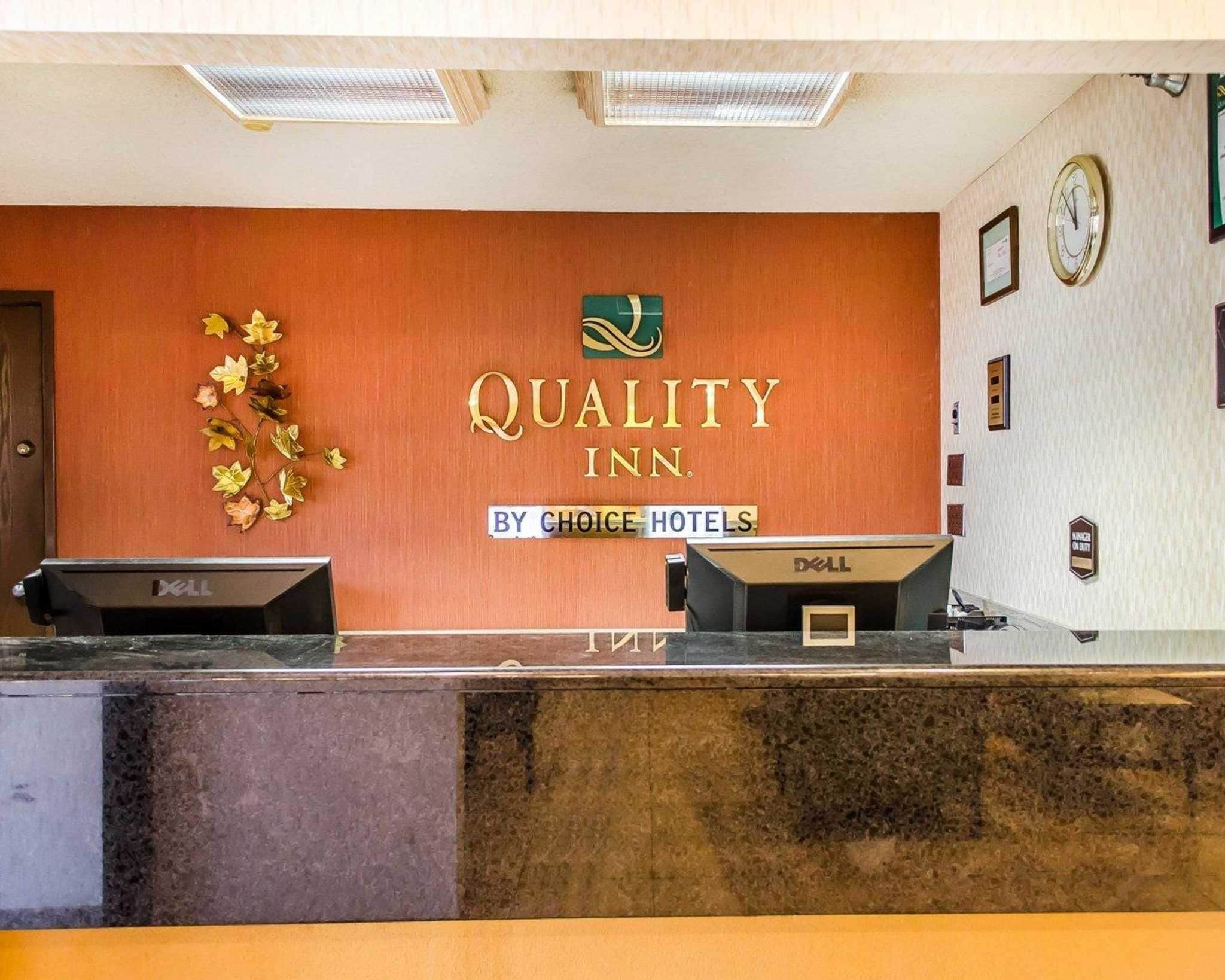 Un comptoir d’accueil d’hôtel avec une enseigne indiquant : « Quality Inn by Choice Hotels ».