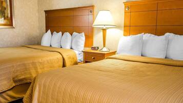 A hotel room with two beds, a nightstand with a lamp, and a painting on the wall.