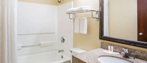 Un baño con bañera, inodoro, lavabo y un perchero con toallas.