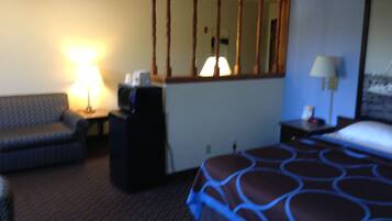 A hotel room with a bed, a desk, a chair, a lamp, and a mirror.