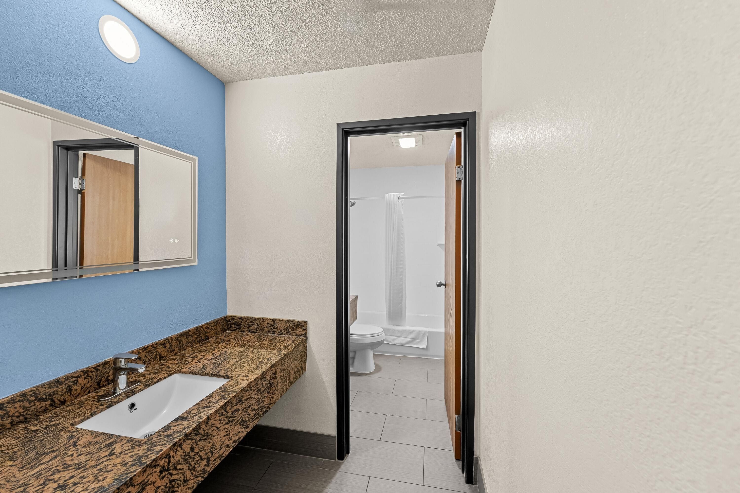 Baño con lavamanos, espejo y zona de ducha.