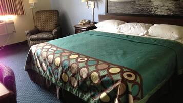 Una habitación de hotel con cama, una silla, una mesita de noche y una lámpara.