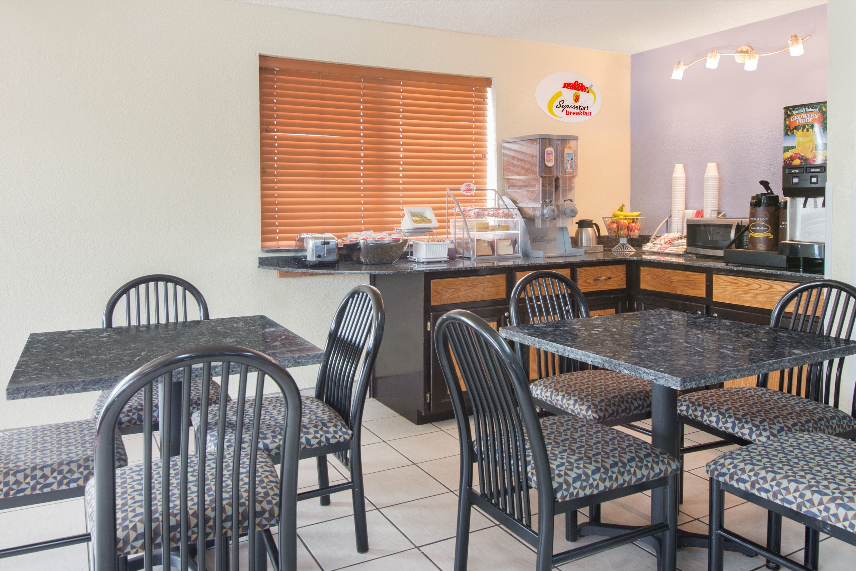 A breakfast bar with seating, a coffee machine, and a fruit display.