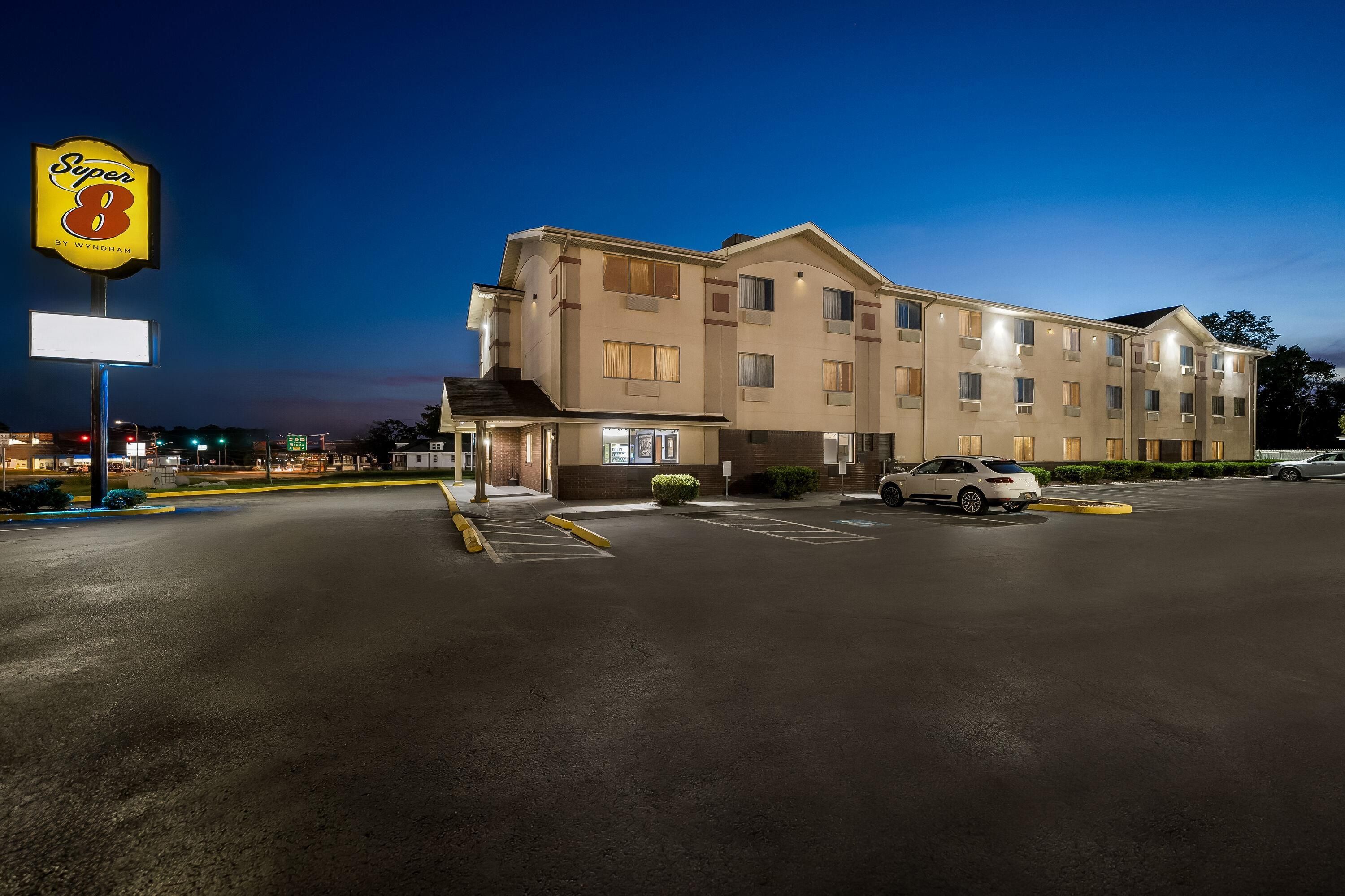 A multi-story hotel with a parking lot, a sign for 'Super 8 by Wyndham', and a few cars parked.