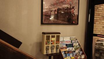 A wall-mounted painting of a train, a vintage-style vending machine, and a display of travel guides and maps.