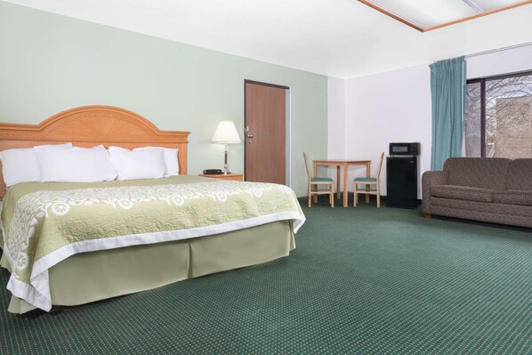 Una habitación de hotel con cama, escritorio, silla, sofá y microondas.