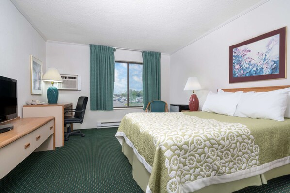 Une chambre d’hôtel avec un lit, un bureau, une chaise, une télévision, une lampe et un tableau au mur.