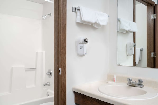 A bathroom with a bathtub, a sink, a mirror, and a towel rack. - Days Inn by Wyndham St Cloud (St Cloud)